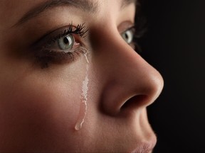 Closeup of young women with tears streaming down face.