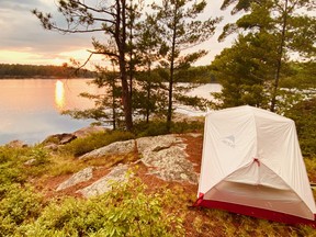 A tent on a rock overlooking a sunset