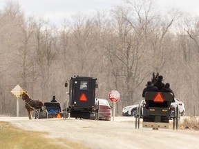 Three horse-drawn buggies, on Tuesday, Dec. 19, 2023, pass the scene of a fatal collision Monday between a vehicle and a horse drawn buggy northwest of Milverton that killed a 13-year-old boy and injured his younger brother. (Mike Hensen/The London Free Press)