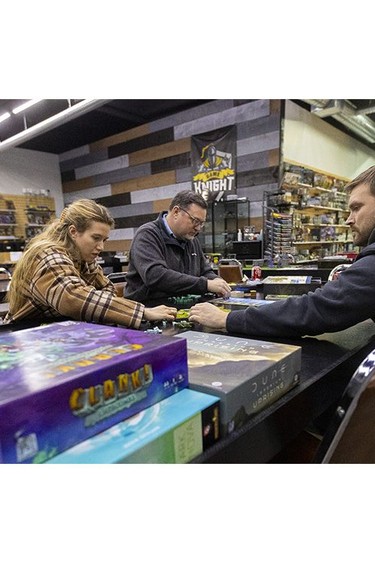 Maya Wilkinson, Jamie Guillemette and Jacob Runnalls set up a board game at Game Knight in London on Tuesday, Nov. 28, 2023. The venue, owned by Tristan and Patience Mitchell, caters to people who like to get together to play games and hang out. (Mike Hensen/The London Free Press)