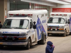 A woman walks by the emergency department at Mount Sinai Hospital in Toronto, Ontario, where a fleet of ambulances wait on January 5, 2022.