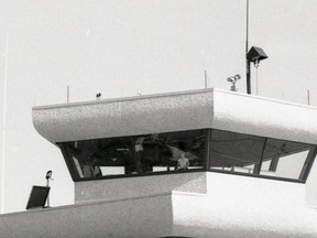 1984.1400.005 – An observer, in 1984, is seen looking out window of Flight Services cupola, atop Peace River airport terminal building, completed and officially opened August 1984. By 2023, there is no NAV Canada staff presence in cupola. However, flight safety measures are maintained.