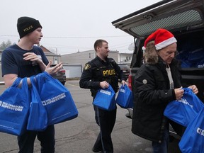 Matt Sanchuk, from left, Norfolk OPP's Colton Hearn, and Ed Sanchuk Sr help unload chocolate gifts to be given away at the Delhi United Church Christmas Day dinner on Monday. CHRIS ABBOTT