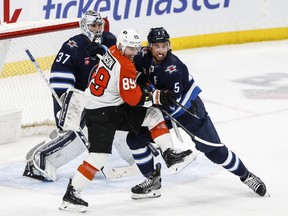 Winnipeg Jets' Brenden Dillon (5) defends against Philadelphia Flyers' Cam Atkinson (89) in from of goaltender Connor Hellebuyck (37) during second period in Winnipeg on Saturday.