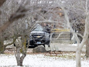 An Ontario Provincial Police officer stands next to an OPP SUV parked near the front entrance of a home at 4022 Wardell Dr. in North Middlesex on Friday, Jan. 12, 2024. (Derek Ruttan/London Free Press)