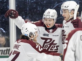 Quinn Bonnie, left, Brody Partridge and Ryder McIntyre of the Peterborough Petes celebrate after Partridge scored the first goal of the game against the London Knights at Budweiser Gardens in London on Friday, Jan. 26, 2024. (Derek Ruttan/The London Free Press)