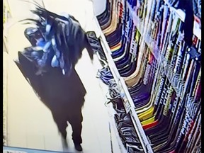 A person carrying $38,000 worth of hockey sticks and hockey gloves during a theft from the Cataraqui Canadian Tire in Kingston, Ont., on Tuesday, January 16, 2024.
