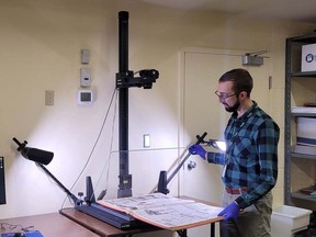 Joshua Klar, archivist with Norfolk County Archives, uses a new state-of-the-art overhead archive scanner to digitize a newspaper. CONTRIBUTED