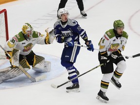 Paul Christopoulos, right, of the North Bay Battalion, blocks a shot as Quentin Musty, middle, of the Sudbury Wolves, and Battalion goalie Dom DiVincentiis look on during OHL action at the Sudbury Community Arena in Sudbury, Ont. on Friday January 26, 2024.