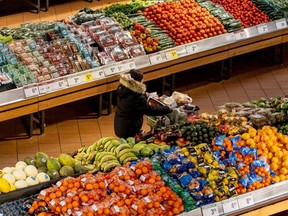 A shopper pushes a cart through the produce section of a grocery store on Nov. 22, 2022.