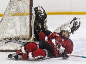 Noah Cowan of the St. Thomas Aquinas Flames takes out Jackson Joseph, goalie for the Mother Teresa Spartans, in Game 2 of the TVRA Central AAA boys hockey semifinal at Carling arena in London on Wednesday, Feb. 21, 2024. (Mike Hensen/The London Free Press)