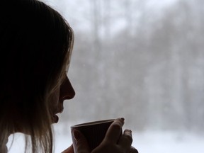 Stock photo of woman with mug of hot beverage against grey winter background