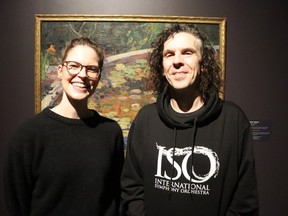 Sonya Blazek, curator of the Judith and Norman Alix Art Gallery in Sarnia, left, and Anthony Wing, executive director of the International Symphony Orchestra, stand with the painting Lily Pond featured in the gallery's new Re View exhibition opening Friday. Wing composed a short musical response to the painting which will be performed Friday evening by a quartet of musicians from the orchestra.