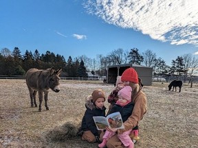 Damaris Koppert sits with her children at Kloud 9 Acres to read Snickers Gets a Visitor.  From left are Gunnar, Mabel and Mia.  The real-life Snickers is on the left.  SUBMITTED