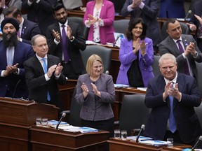 Minister of Finance Peter Bethlenfalvy, second left, and members of the legislature including Premier Doug Ford, right, applaud as he tables the Ontario provincial budget at the legislature at Queen's Park in Toronto on Tuesday, March 26, 2024.