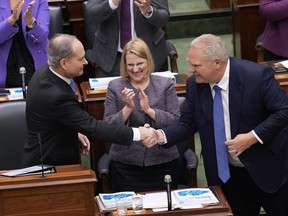 Finance Minister Peter Bethlenfalvy, left, shakes hands with Premier Doing Ford, right, as Health Minister Sylvia Jones looks on after Bethlenfalvy tabled the Ontario budget at the legislature at Queen's Park in Toronto on Tuesday, March 26, 2024.