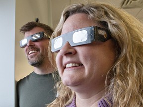 Brantford Public Library manager of communications and community engagement James Clark, and administrative assistant Michelle Male try on special glasses that will allow viewers to safely watch the upcoming eclipse.