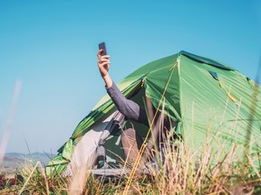Arm with cellphone sticking out of tent