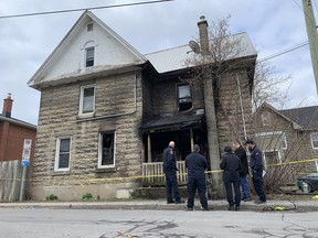 Fire fighters stand in front of a house at the intersection of Chatham and Colborne streets where fire sent several people to hospital early Thursday morning in Kingston