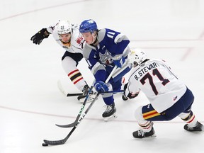 Landon McCallum, middle, of Sudbury Wolves, attempts to skate between Thomas Stewart, left, and Bode Stewart, of the Barrie Colts, during OHL action at the Sudbury Community Arena in Sudbury, Ont. on Friday March 22, 2024.