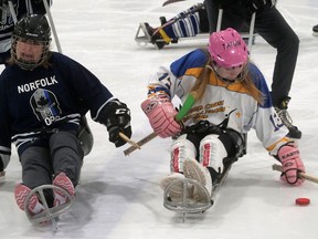 Tatum Wilkes, right, on the South Coast Special Needs Kids sledge hockey team, is defended by Tamara Brooks-Wheat, Norfolk County OPP, during Sunday's exhibition sledge hockey game in Waterford. CHRIS ABBOTT