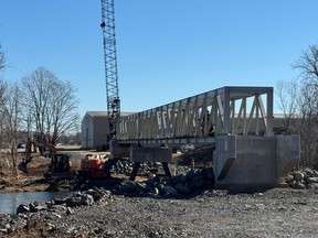 Crews are seen working Tuesday on the the pedestrian bridge over Trout Creek in Sussex.