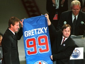 Oct. 1, 1999. The greatest Edmonton Oilers and National Hockey League's (NHL) player of all times, Wayne Gretzky, with the help of his long-time and close friend Edmonton Oilers locker room attendant Joey Moss hold up Gretzky's mini-replica version of the banner at #99 number retirement and banner raising night on Oct. 1, 1999 at the Skyreach Centre in Edmonton, Alta. In the background (right) is the master of ceremonies, long-time and NHL Hall of Fame announcer Rod Phillips. Perry Mah/Edmonton Sun/QMI Agency
