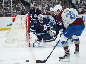 WINNIPEG, CANADA - APRIL 21: Connor Hellebuyck #37 of Winnipeg Jets defends his net against Ross Colton #20 of the Colorado Avalanche in Game One of the First Round of the 2024 Stanley Cup Playoffs at Canada Life Centre on April 21, 2024, in Winnipeg, Canada. (Photo by David Lipnowski/Getty Images)