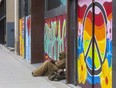 A homeless man rests against an empty building on Richmond Street in London. (Free Press file photo)