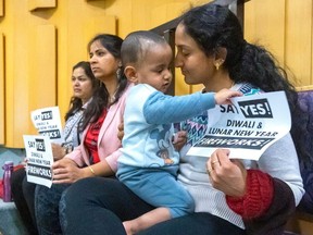 Sowmya Kadaveru holds her one-year-old son Soham Vanam as she watches a debate in city council chambers at London city hall about whether to allow Londoners to set off fireworks on lunar new year and Diwali with her friends Smita Tajne, left, and Veena Jashi on Tuesday, April 2, 2024. (Mike Hensen/The London Free Press)