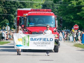 Two individuals carry a banner in the Bayfield Fair parade.