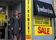 Hulley stands at the front of her store where retirement sale signs are visible.