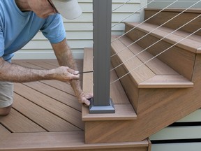 Stock photo man installing newel post on deck/stairs