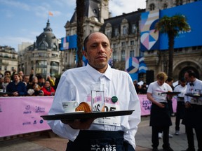 A waiter in work outfits poses before the start of a traditionnal "Course des cafes" (the cafes' race), in front of the City Hall in central Paris, on March 24, 2024. Around 200 participants gathered to compete in the 2km race around Paris' Marais district single-handedly carrying a tray bearing a coffee, a glass of water and a croissant. Founded in 1914, this is the first edition of the race after a 13-year hiatus. (Photo by Dimitar DILKOFF / AFP) (Photo by DIMITAR DILKOFF/AFP via Getty Images)