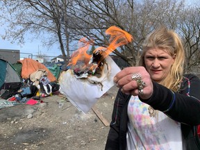 Homeless encampment resident Lacey McNeil burns an order to leave Belle Park she received Tuesday as Kingston bylaw officers begin enforcing the daytime camping ban in Kingston, Ont. on Monday, April 2, 2024.