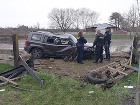Ontario Provincial Police officers surround a damaged SUV which was driven off County Road 1, rolled and struck a hydro pole in Napanee, Ont., on Sunday, April 14, 2024.