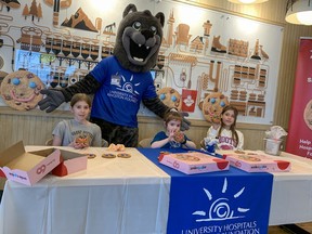 Harper Russell, left, Collins Russell, and Peyton Strawbridge, along with University Hospitals Kingston Foundations mascot Asher, get to try their hands at decorating with the classic pink and blue icing during the Smile Cookie 2024 campaign kick off at the MacDonnell St Tim Hortons in Kingston, Ont. on Friday, April 19, 2024.