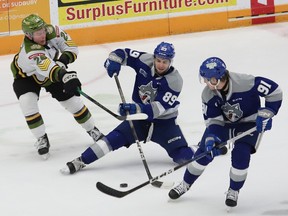 Nathan Villeneuve, middle, of the Sudbury Wolves, attempts to keep control of the puck while Ty Nelson, left, of the North Bay Battalion, attempts to knock Villeneuve off the puck during OHL playoff action at the Sudbury Community Arena in Sudbury, Ont. on Tuesday April 16, 2024.