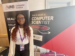 Zammie Igwe is standing in front of signs promoting computer science.