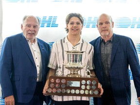 London Knight forward Easton Cowan is flanked by Ontario Hockey League commissioner David Branch, left, and team manager Mark Hunter after being awarded the Red Tilson Trophy as the league’s most outstanding player at Budweiser Gardens in London on Thursday, May 2, 2024. (Derek Ruttan/The London Free Press)