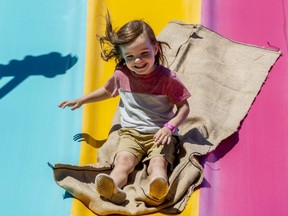 Julian Sleegers, 3, smiles at his mom as he rides down a slide at the London Children's Festival in Victoria Park on Friday June 17, 2022. (Mike Hensen/The London Free Press)