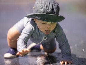 Wesley Fraser, 15 months old, crawls toward his parents at the Gibbons Park splash pad in London.  (Mike Hensen/The London Free Press)