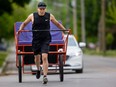 Johannes Lamoureux pulls his rickshaw down William Street in London, Ont. Photograph taken on Thursday May 9, 2024. (Mike Hensen/The London Free Press)