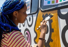 Louange Kirangirire, 17, a student in the Beal art program, paints a portion of a mural drawn on a Boys' and Girls' Club of London bus by London artist Andrew Lewis on Tuesday, May 21, 2024. (Mike Hensen/The London Free Press).