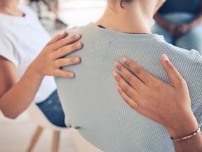 Stock photo of hands on someone's back, providing emotional support