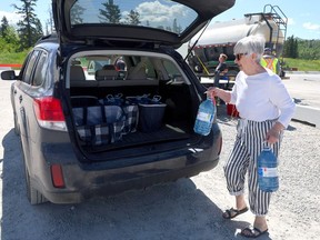 A Calgary resident loads water taken from the Bow River in Calgary into her vehicle on Tuesday, June 25, 2024. The city is asking residents to reduce water usage following a break in a water main on June 5. (Darren Makowichuk/Postmedia)