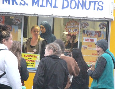 Jessica Tuckey, Jigna Trivedi and Zaden Thacker, of Mrs. Mini Donuts, serve customers at Poutine Feast at Downtown Plaza in Sault Ste. Marie, Ont., on Friday, June 28, 2024. (BRIAN KELLY/THE SAULT STAR/POSTMEDIA NETWORK)