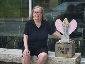 Rose Simpson sits with the sculpture of an angel beside a bench in front of the Cancer Centre at The Ottawa Hospital. Less than three months after initial diagnosis, she was cancer-free.