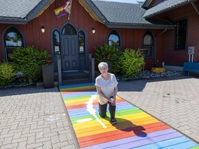 Gale Connor, a member of the board of directors at the Station Arts Center in Tillsonburg, stands on the center's rainbow boardwalk that was damaged June 9 by someone riding a dirt bike.  The damage from the bike's tire has been covered with paint primer and the full colors will soon be restored.  Photo shot in Tillsonburg on Friday, June 14, 2024. (Derek Ruttan/The London Free Press)