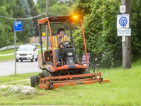 A member of London's Parks and Recreation department cuts grass along Commissioners Road in Byron on Thursday August 12, 2021. (Free Press file photo)